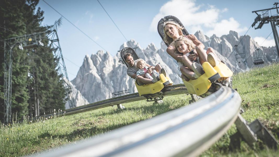 Famiglie che scendono con il bob su rotaia con le Dolomiti sullo sfondo