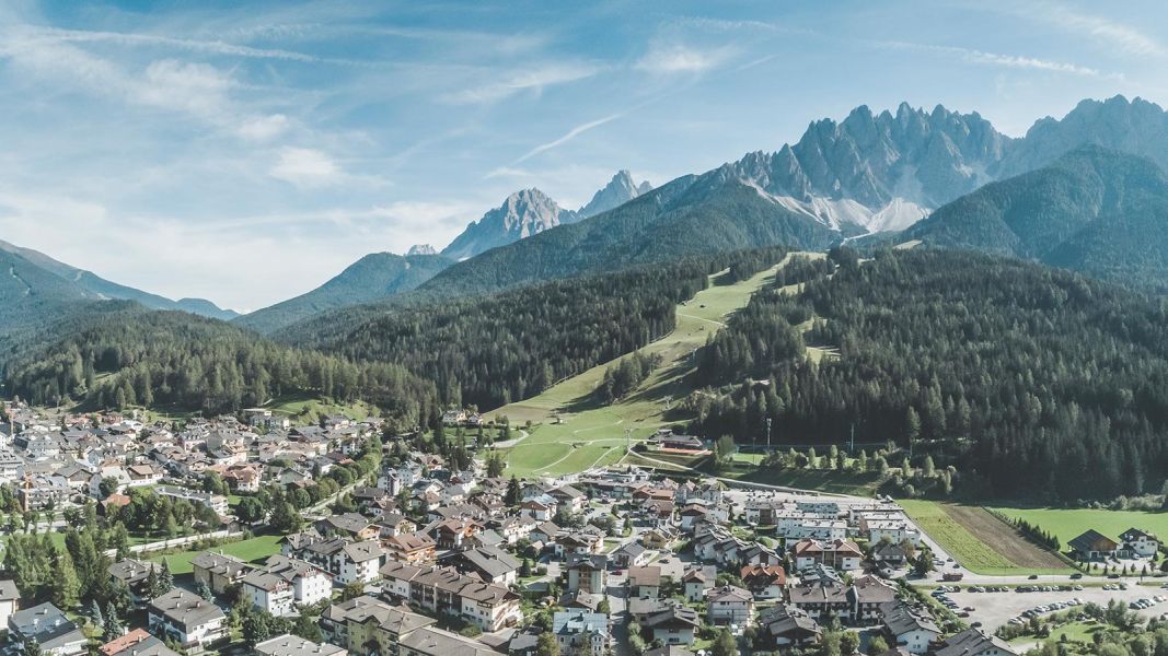 Veduta aerea di San Candido con le piste verdi e le Dolomiti sullo sfondo