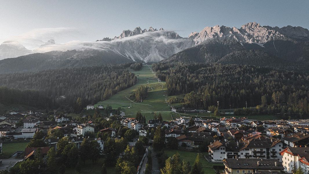 Panorama di San Candido con le Dolomiti e piste verdi illuminate dalla luce del mattino