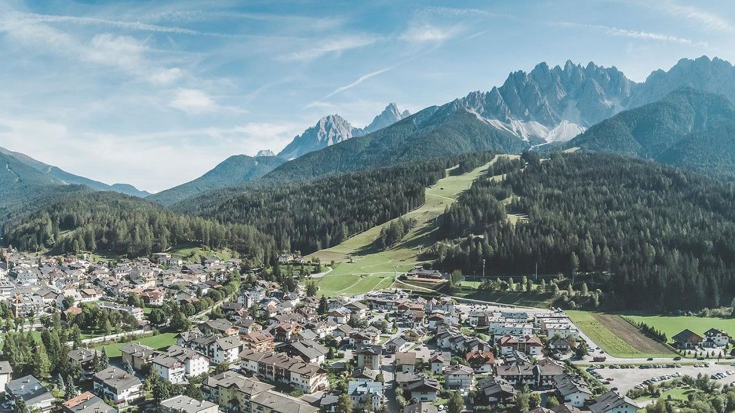 Vista panoramica di San Candido con le Dolomiti e piste verdi in una giornata limpida