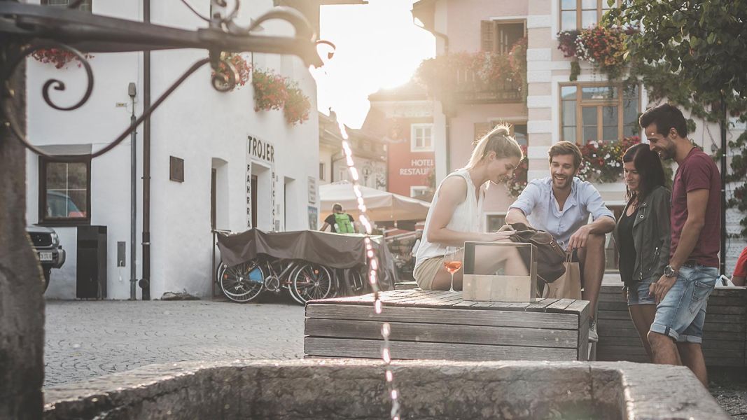 Gruppo di amici seduti vicino a una fontana nel centro di San Candido al tramonto
