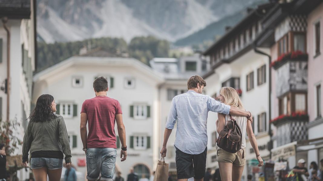 Coppie di giovani che passeggiano nelle vie del centro di San Candido con le Dolomiti sullo sfondo