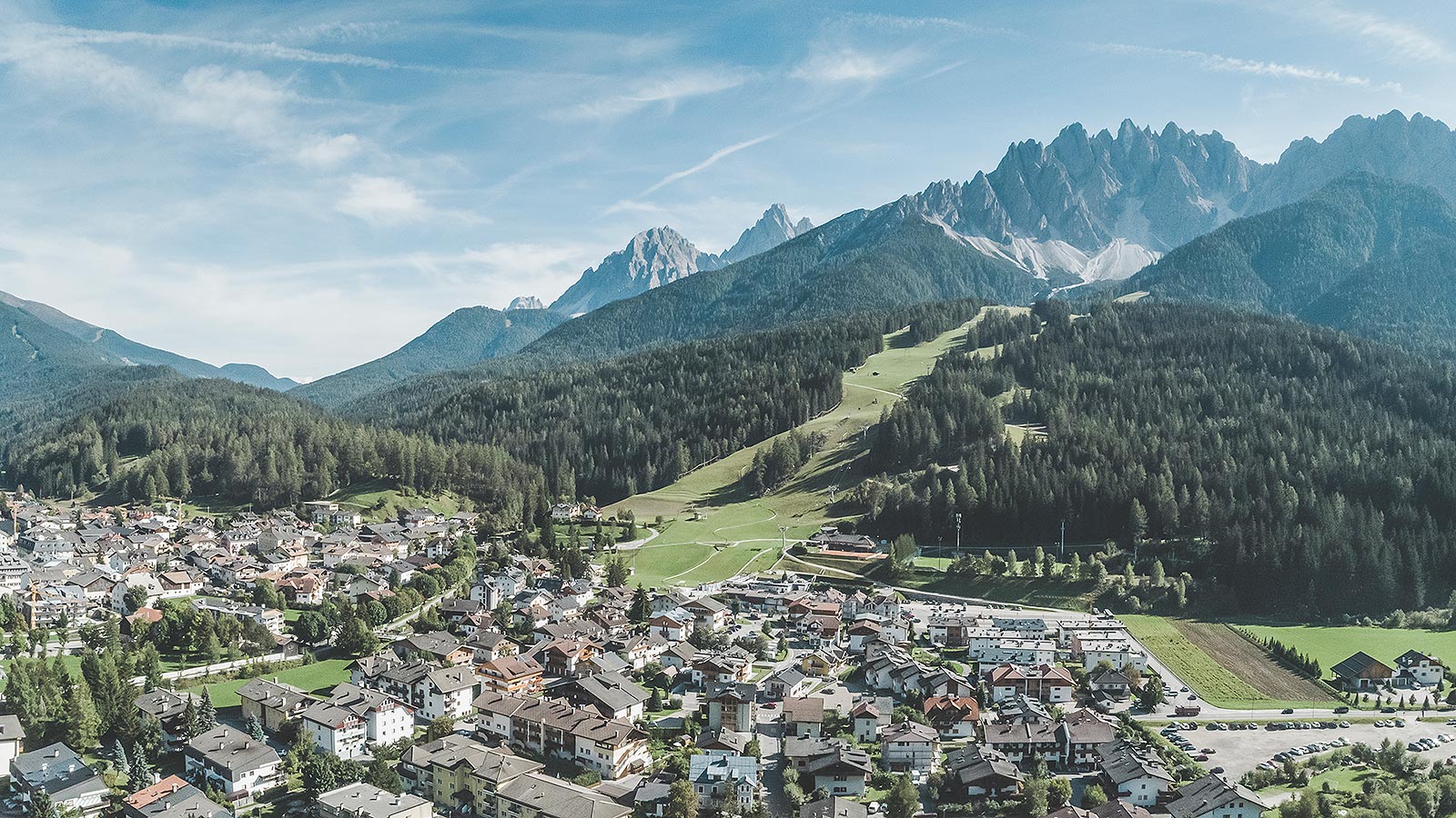 Panorama dall'alto della città con le colline coperte dai boschetti che fanno da sfondo paesaggistico.