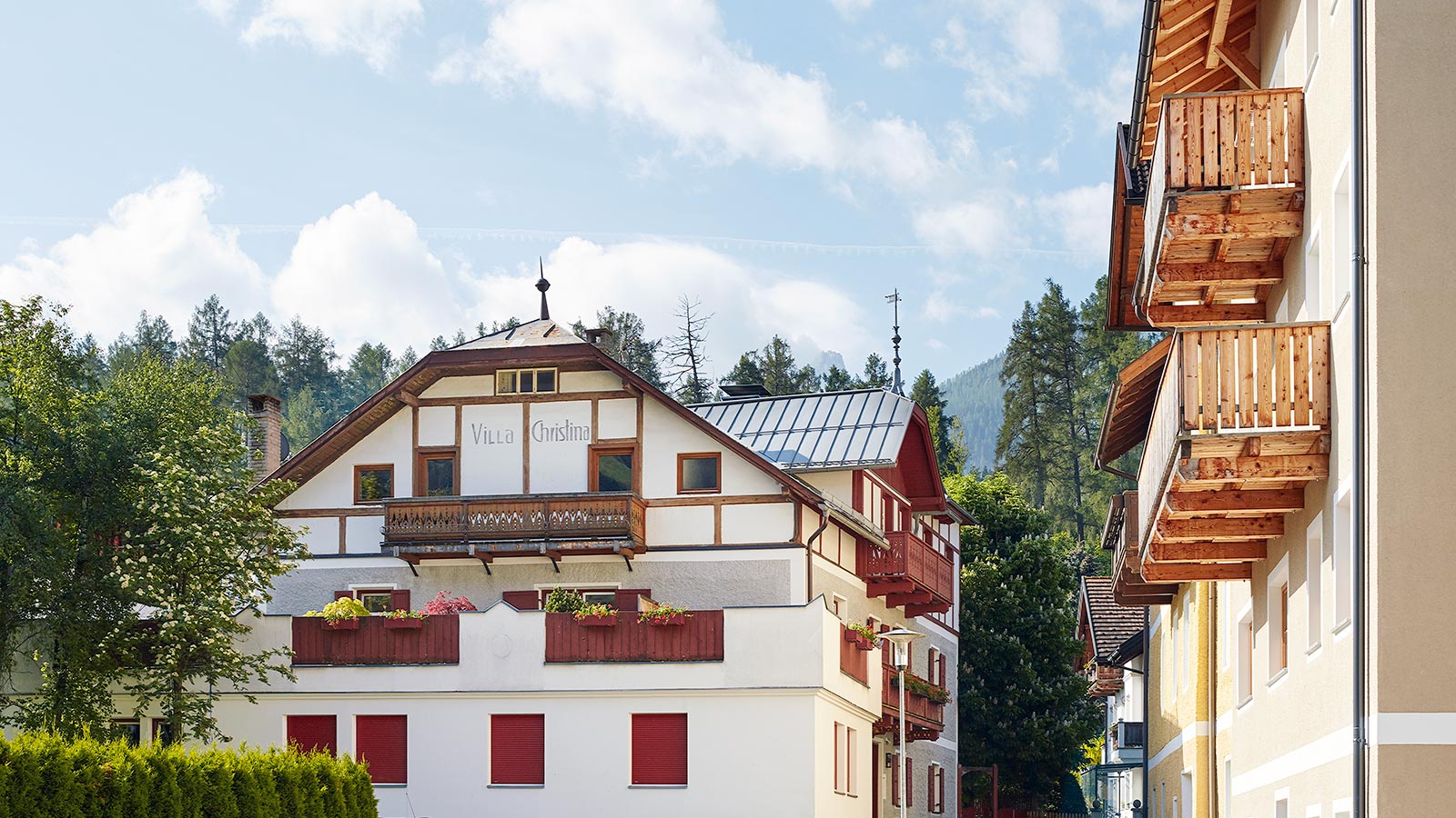 Vorderansicht des Ferienhauses Villa Christina, ein rot-weißes Gebäude mit einer großen Terrasse davor.